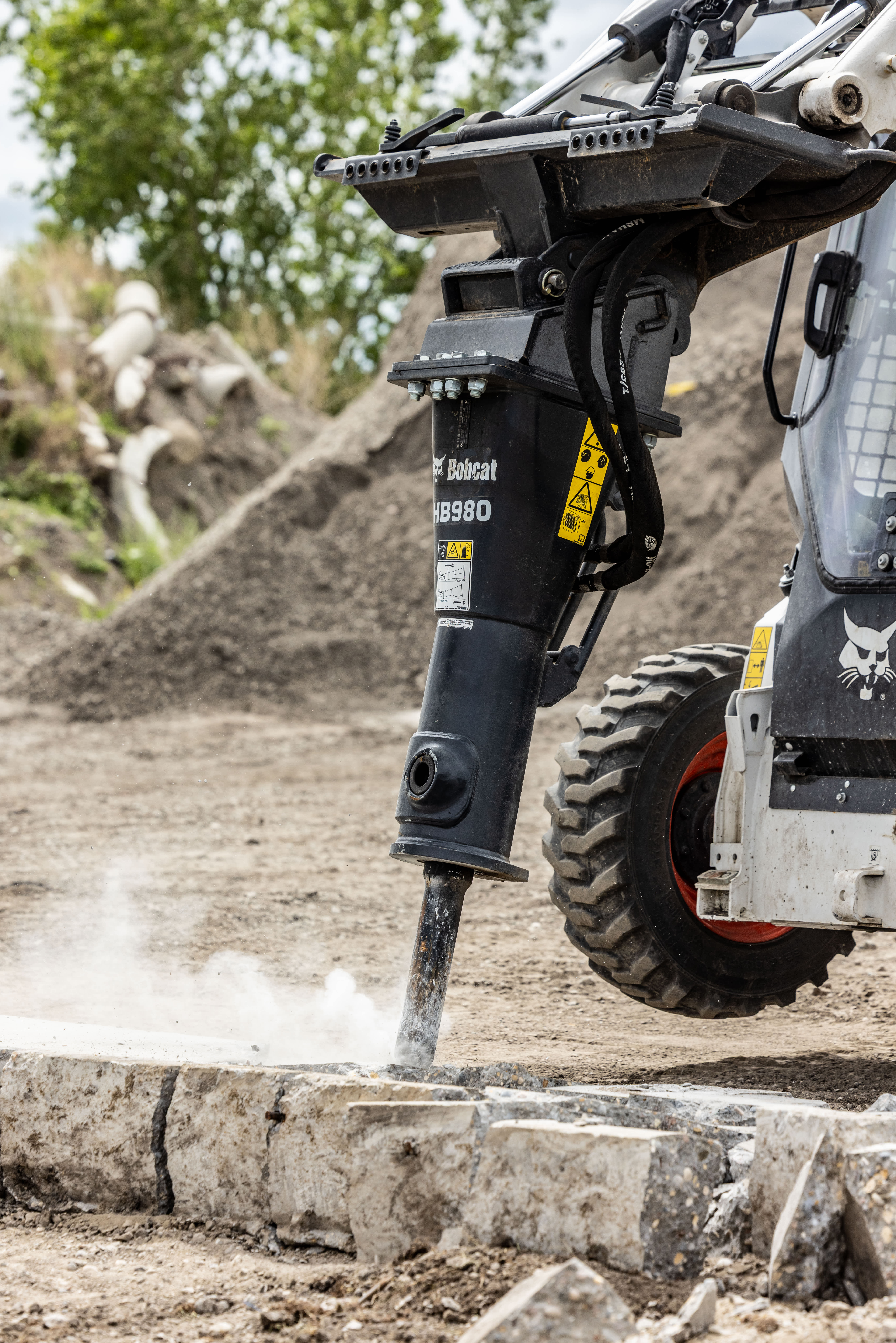 Close-up of a Bobcat HB980 hydraulic breaker attached to a Bobcat skid-steer loader working on a concrete slab