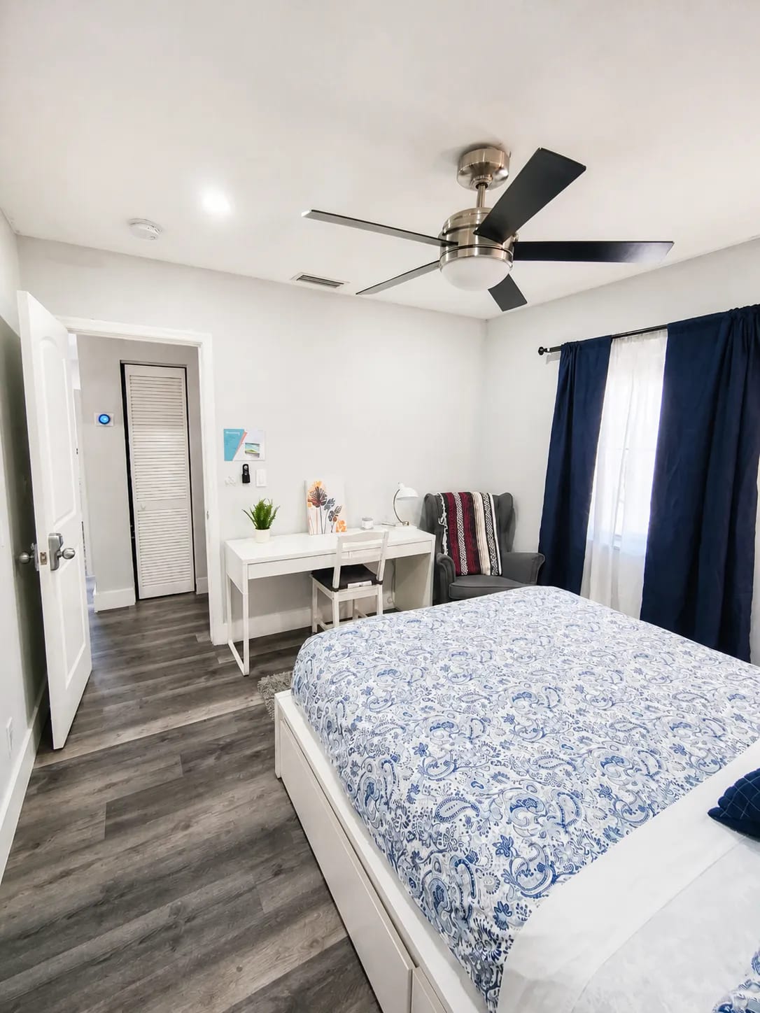 One-bedroom suite with storage bed, dedicated desk workspace, and navy blackout curtains