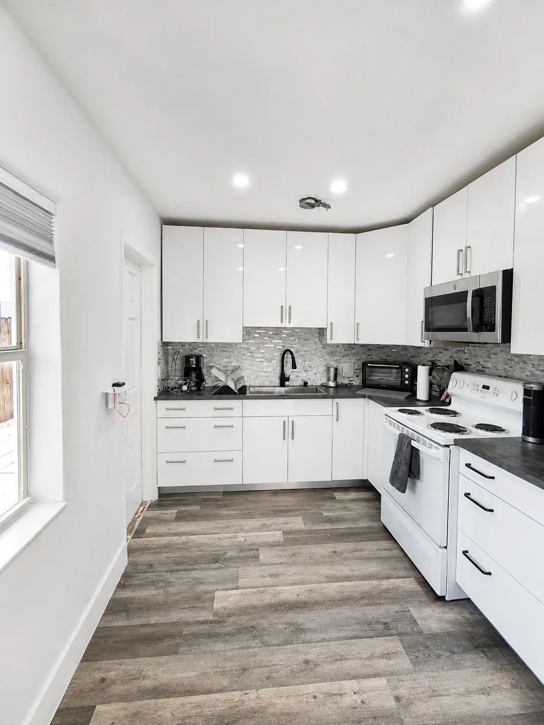 Full one-bedroom kitchen with white cabinets, stove, oven, microwave, and coffee makers