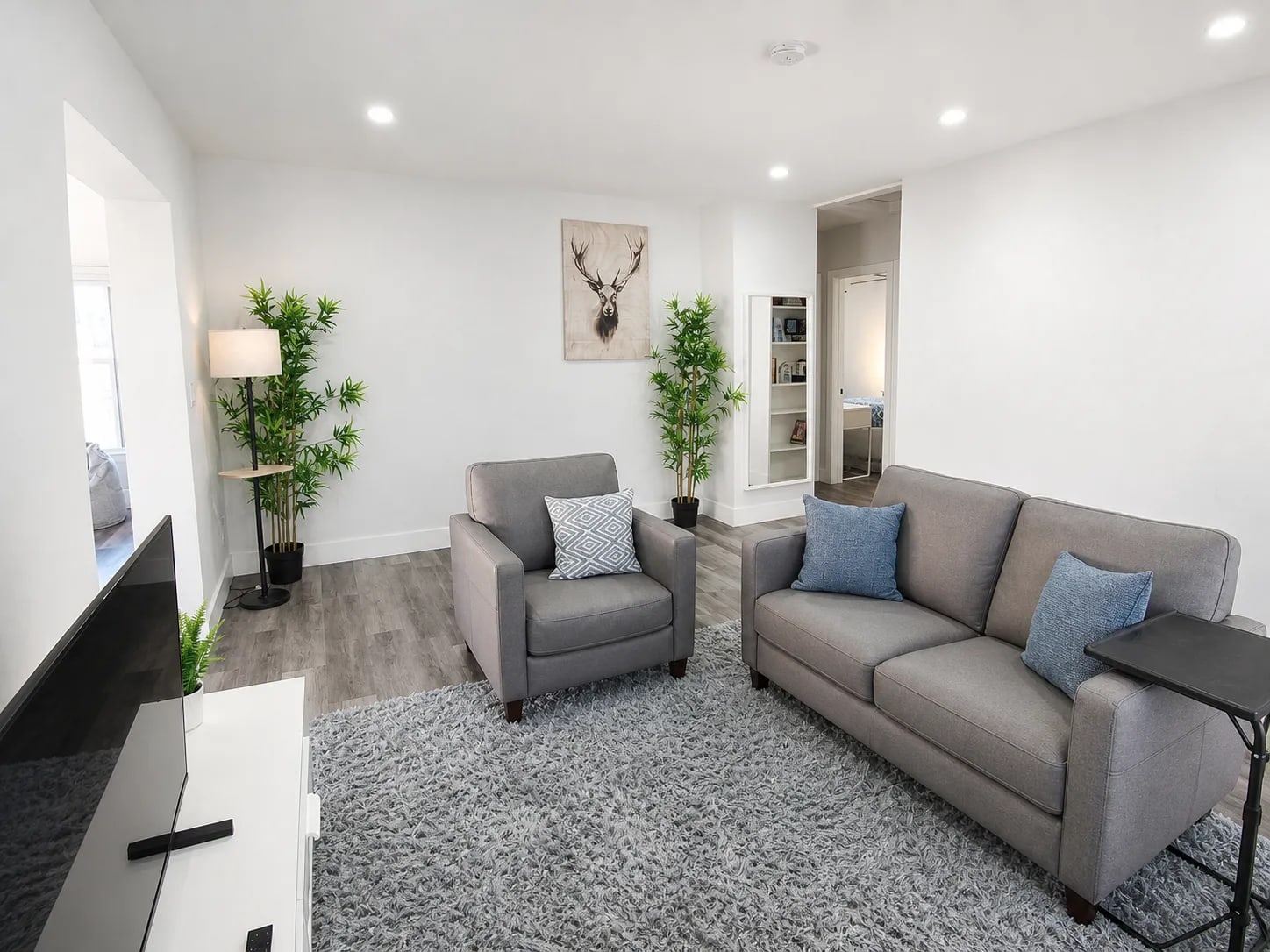 One-bedroom living area looking toward the bedroom with modern seating and recessed lighting