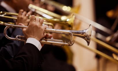 A man in a suit and tie is playing a brass instrument.