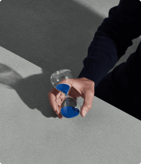 une main tenant un sablier avec du sable bleu