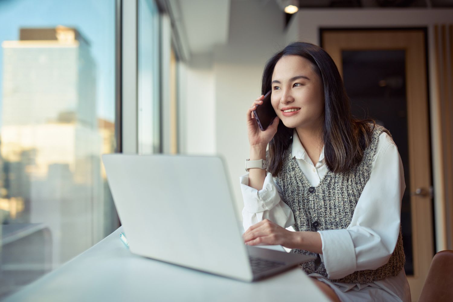 Office worker using a phone and a computer at their desk