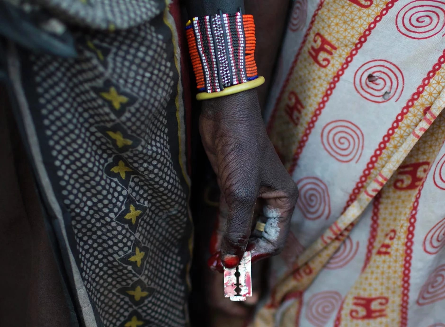 A woman holds a razor blade after performing FGM