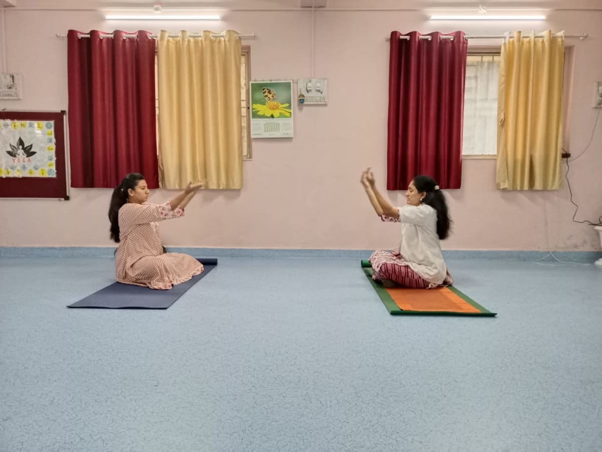 An instructor and student practising seated stretches in the studio