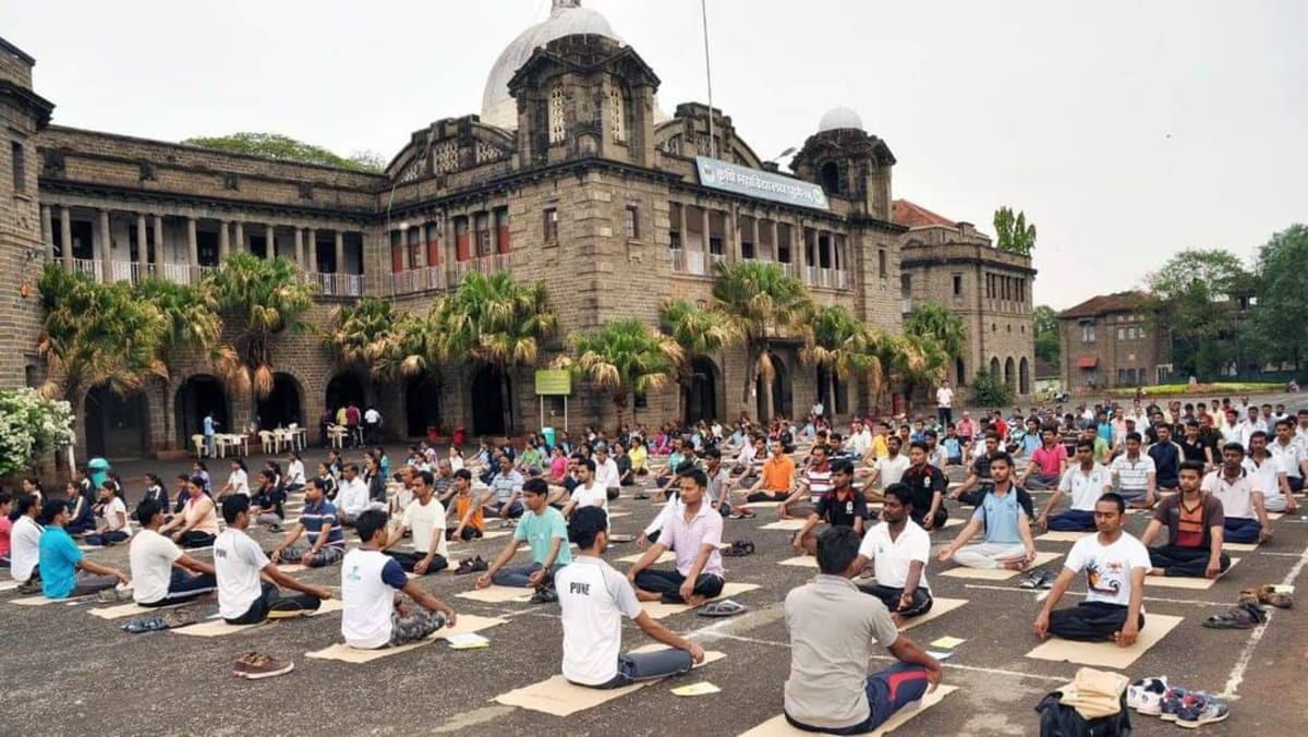 A large group practising yoga in front of a historic building