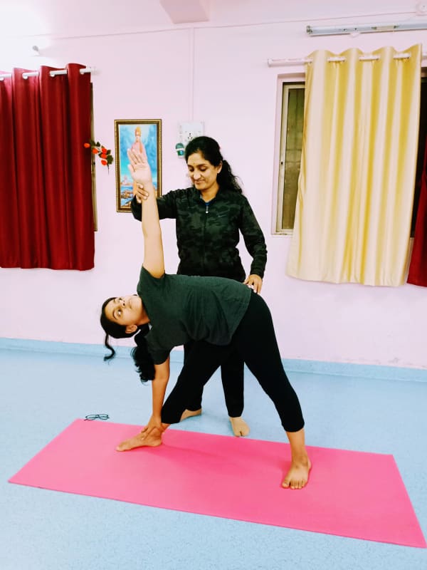 Dr. Manisha guiding a student in a standing yoga posture