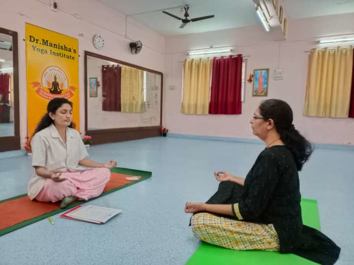 Dr. Manisha speaking with a student seated on yoga mats