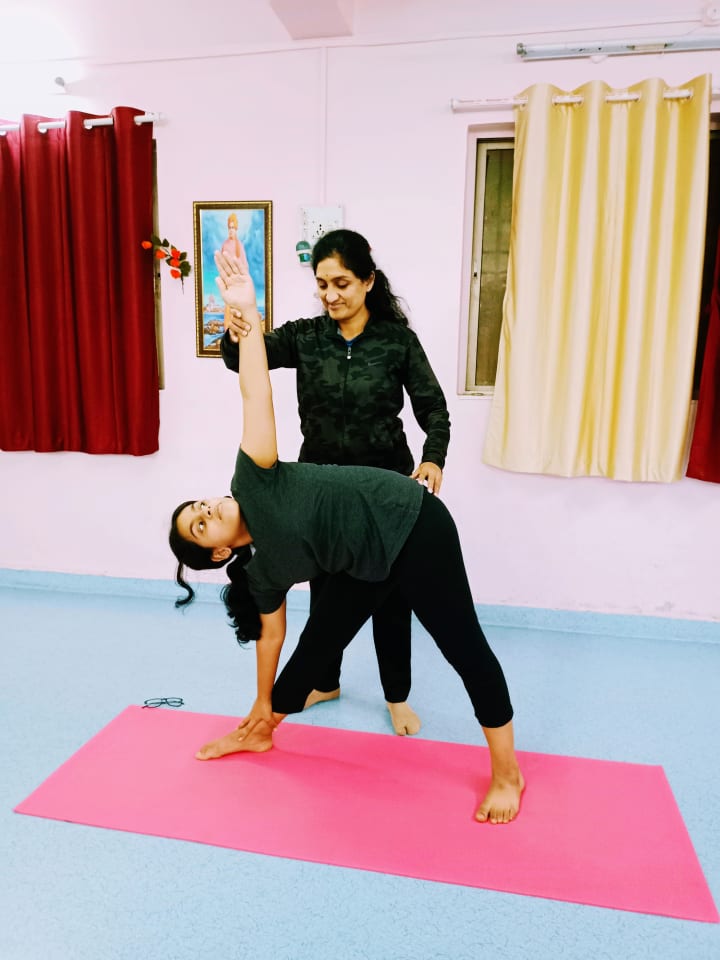 Dr. Manisha guiding a student in a standing yoga posture
