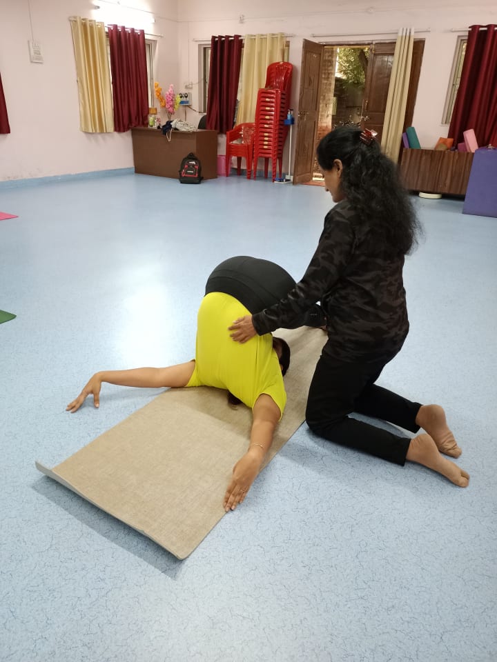 Dr. Manisha supporting a student through a seated yoga stretch
