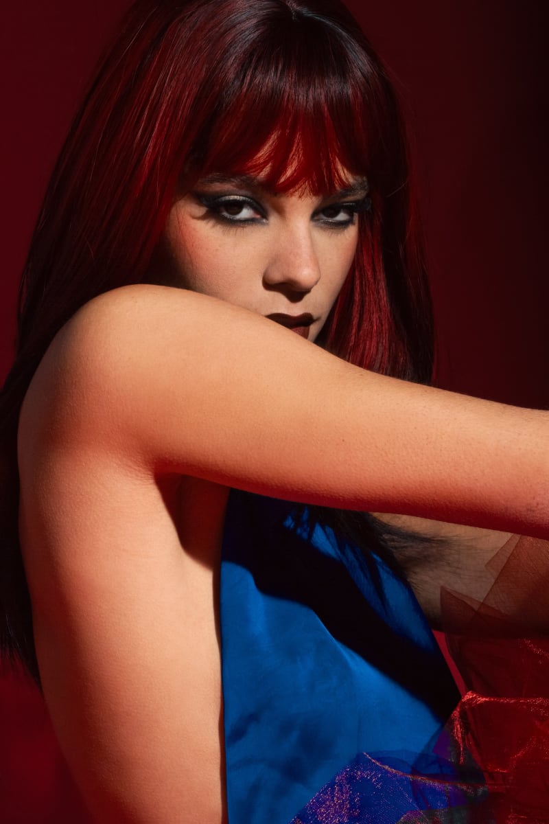 Maquillage éditorial femme allongée robe bleue fond rouge par Léna makeup artist Paris
