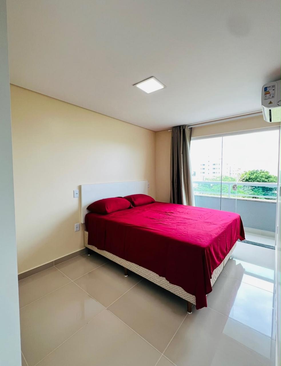 Dormitorio con cama matrimonial, aire acondicionado y ventanal al balcón