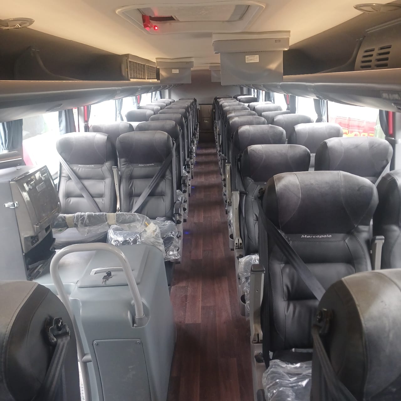 Interior del bus: butacas tapizadas a ambos lados del pasillo