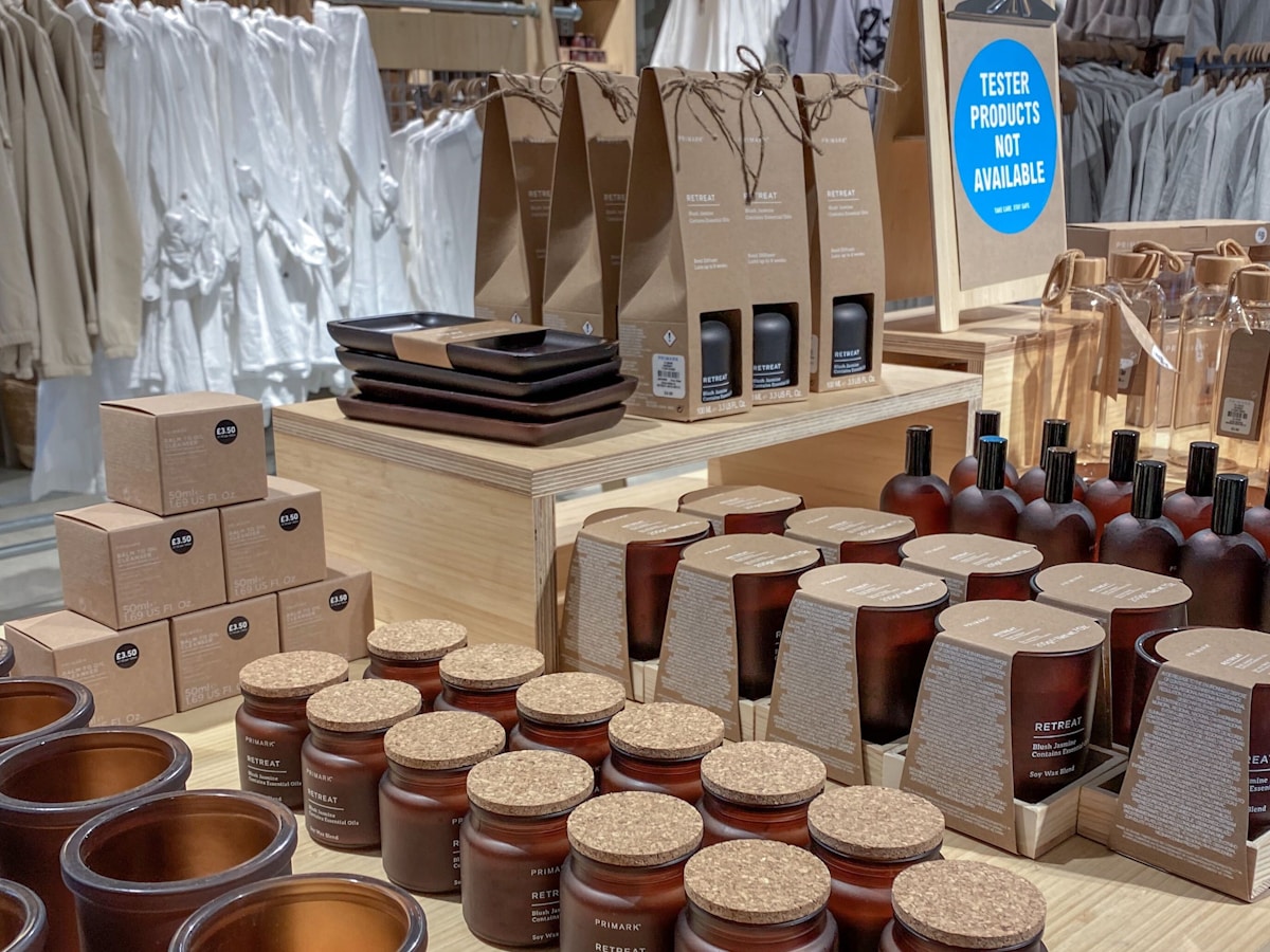 Premium retail boutique with warm earthy tones, natural wood shelving, warm spotlight illumination