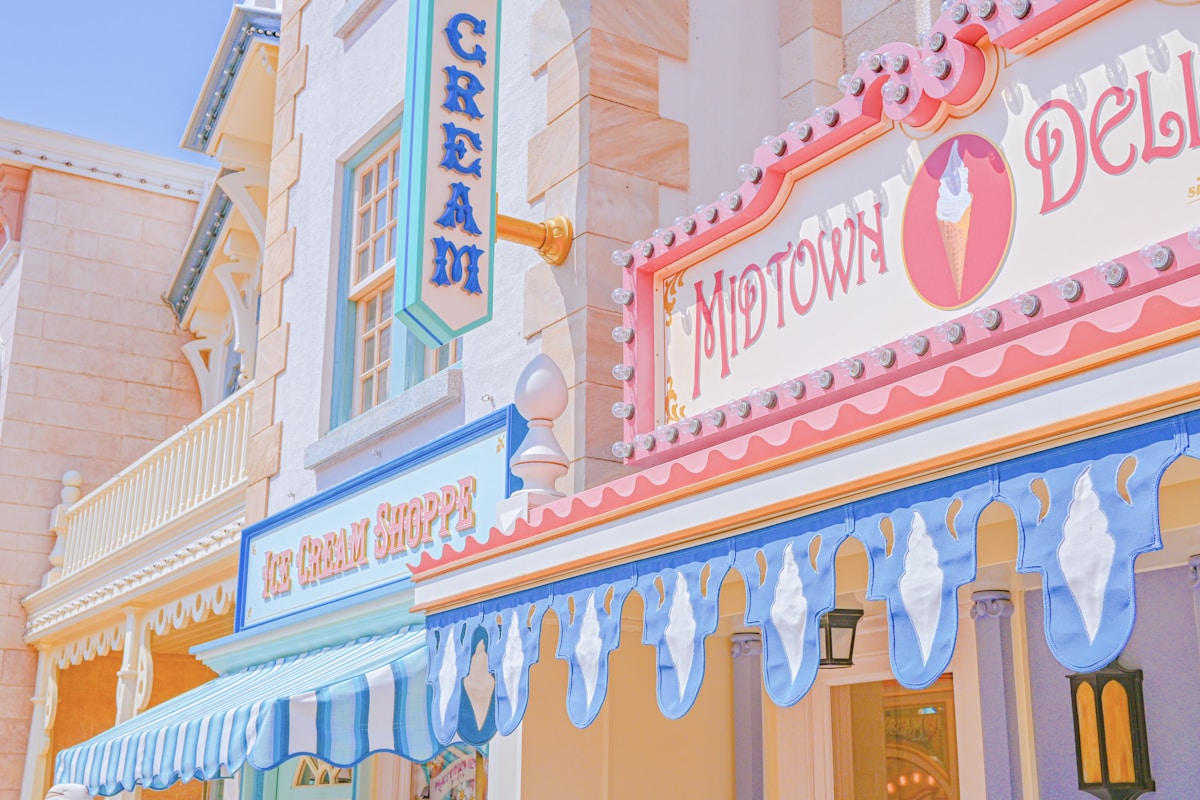 Bright pastel ice cream shop storefront with pink and cream decor, warm overhead lighting, cheerful display cases