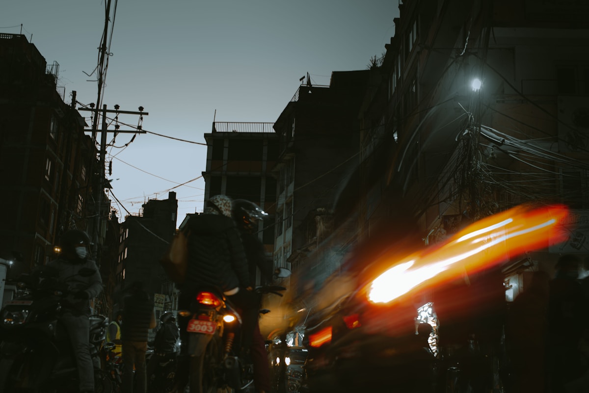 Bold orange motorcycle on dark asphalt road at night, dramatic low-angle shot with motion blur and city lights