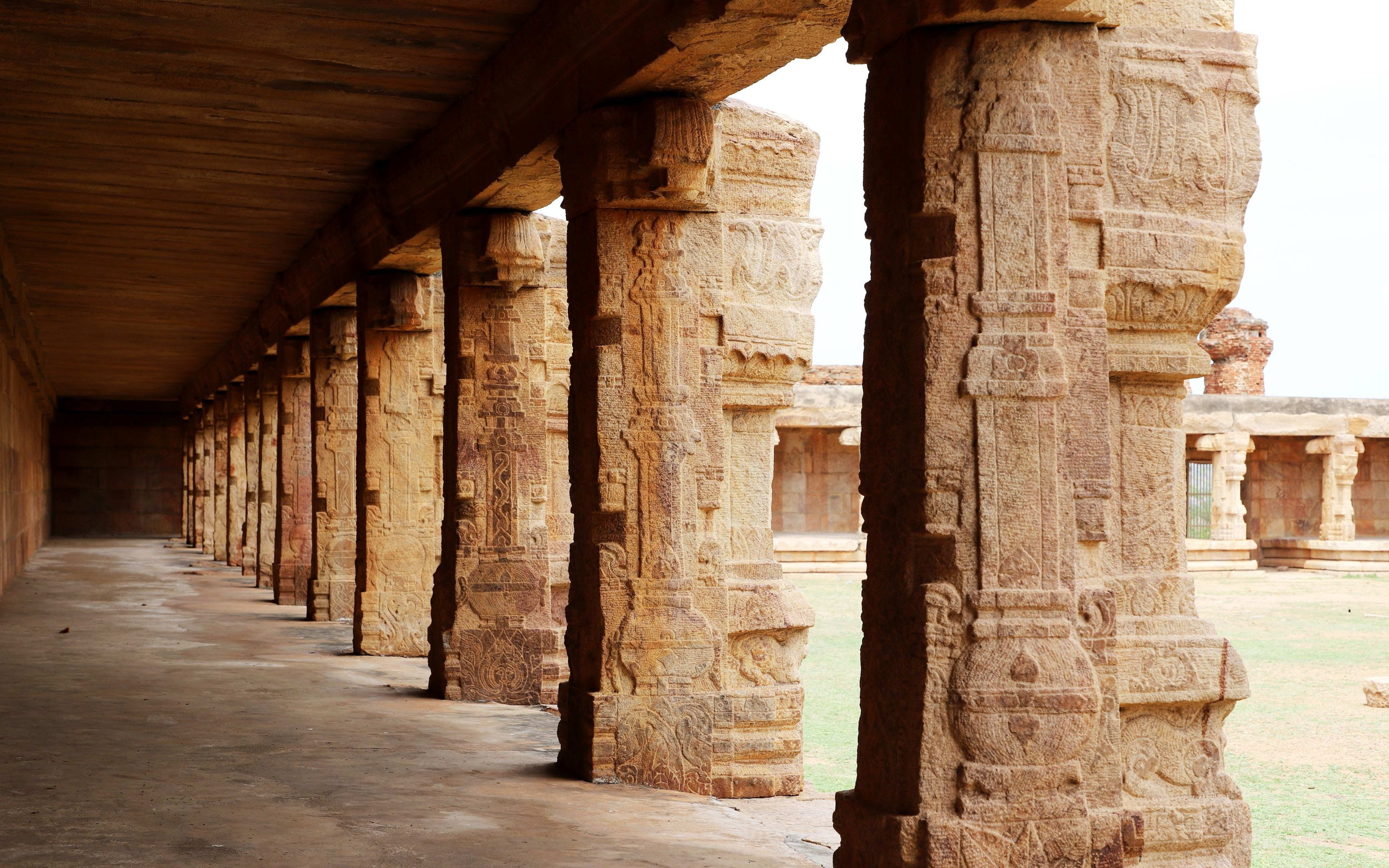 A long corridor of carved stone pillars inside a temple