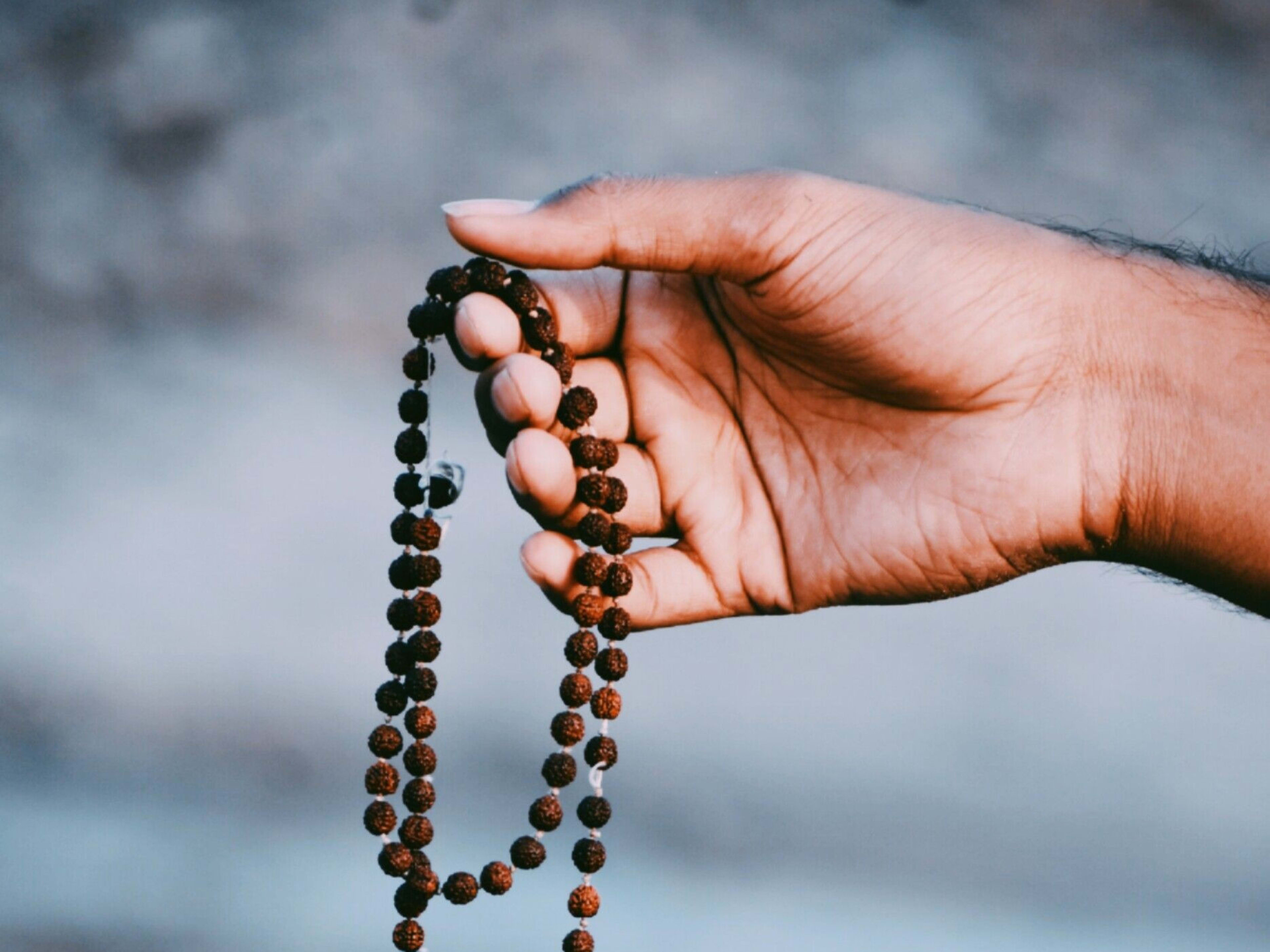 A hand holding a rudraksha mala