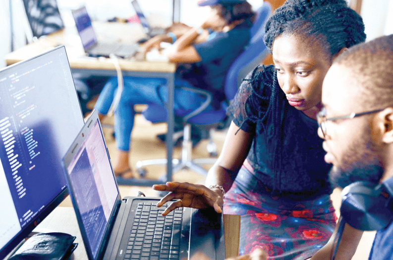 Photo of an employee showing her colleague tasks on his computer. /STREAMLINE