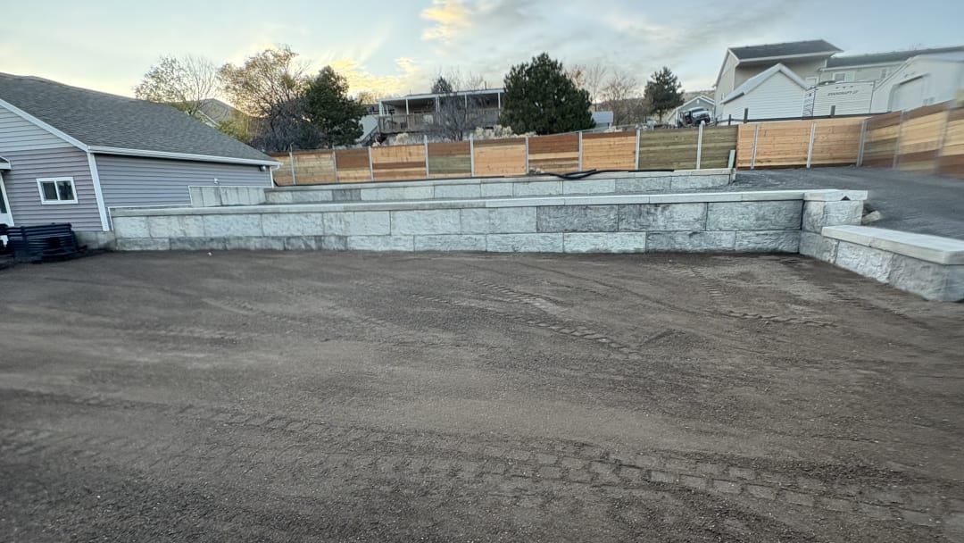 Block retaining wall above a backyard regraded with fresh dark topsoil