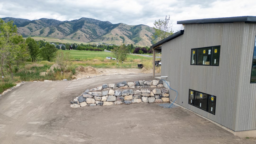 Completed boulder retaining walls with the pad rough-graded beside the building