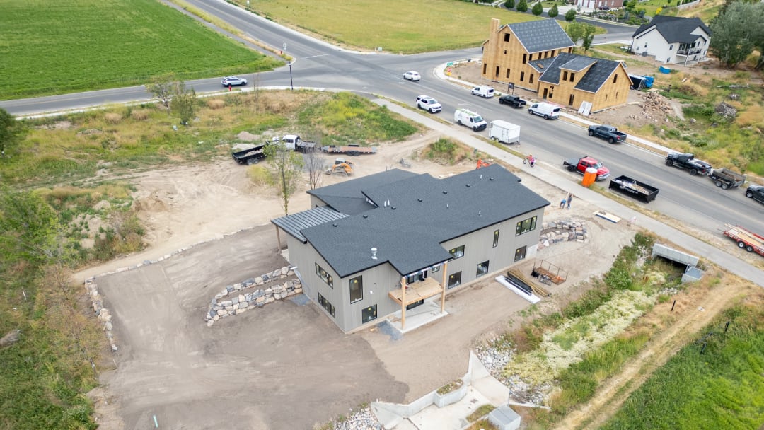 Drone view of a home with rock retaining walls and freshly graded pads