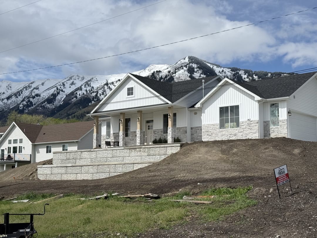 Two-tier block retaining wall stepping a graded front yard up to a new home