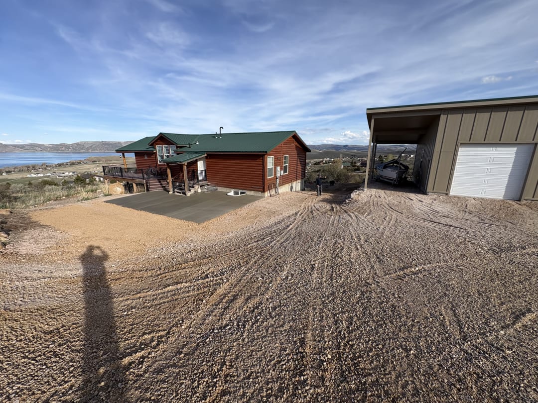 Lakeside property with a new gravel drive, concrete pad, and shop building