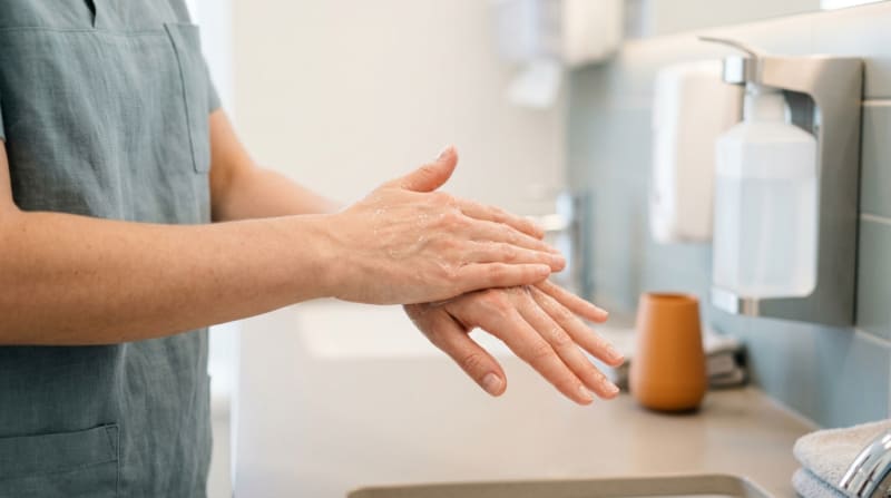 Nahaufnahme von Haenden beim korrekten Einreiben von Haendedesinfektionsmittel