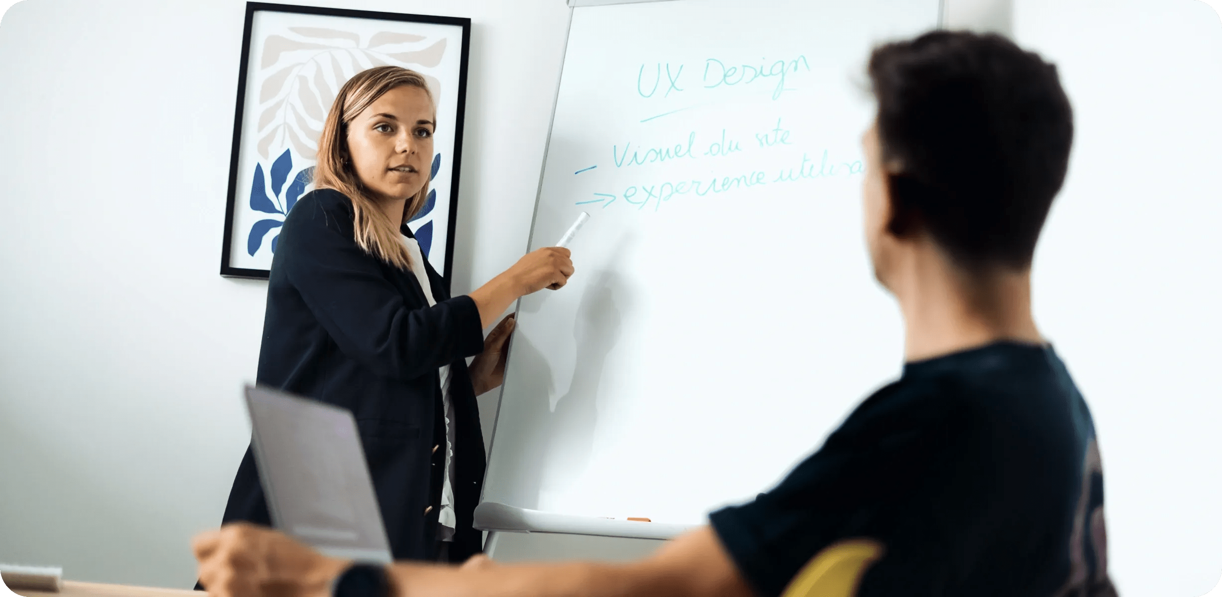 Femme présentant des notes de UX design sur un tableau blanc à un collègue
