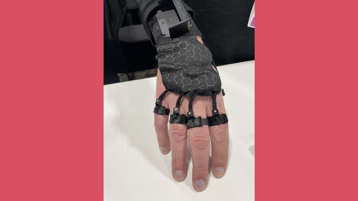 Close up on a white mans hand wearing the Afference haptic device with rings around each finger and a harness on the back of the hand leaving the palm free