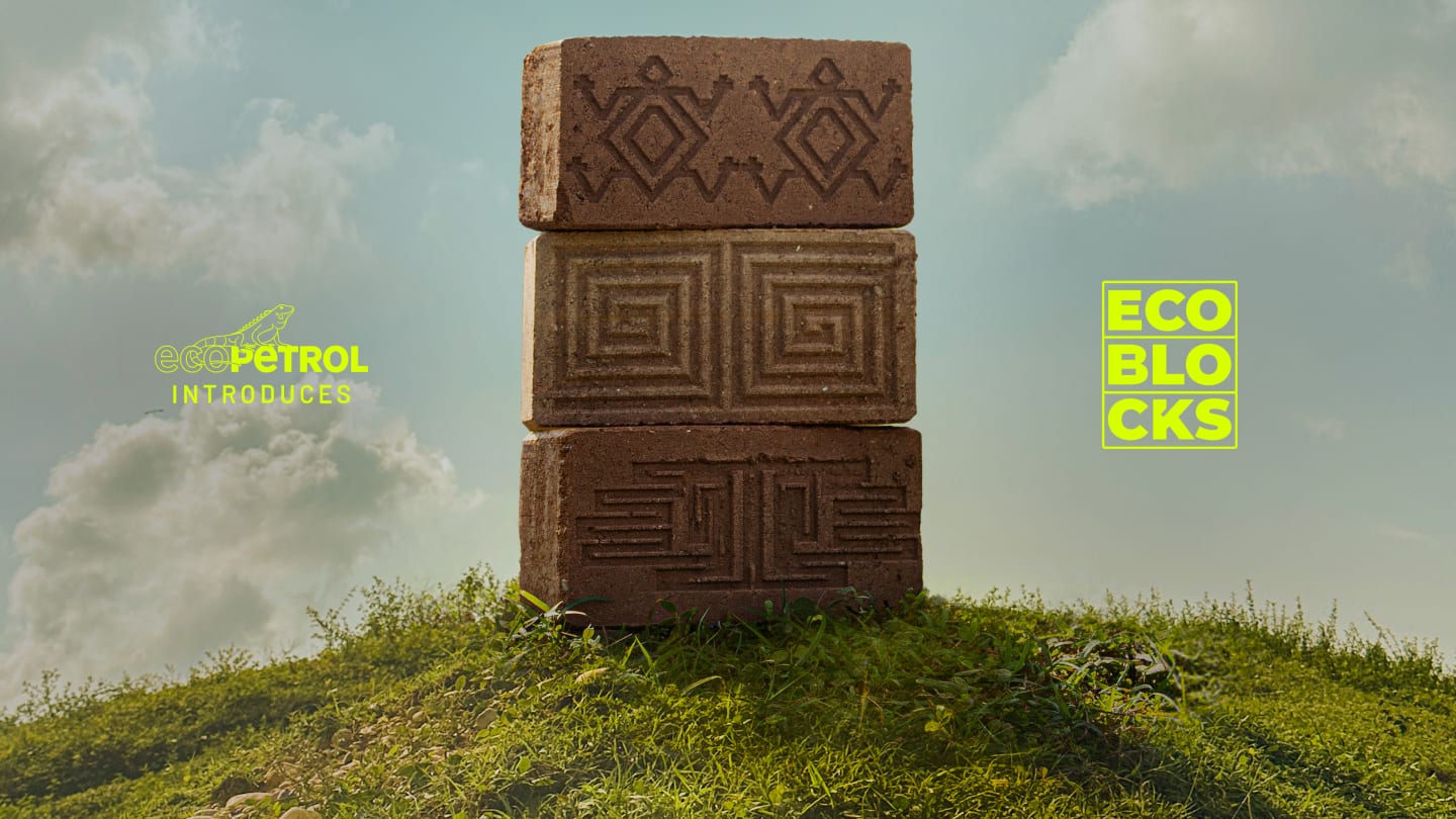 Three patterned brown bricks stacked on a grassy hill under a cloudy sky with the text Ecopetrol introduces EcoBlocks in yellow.
