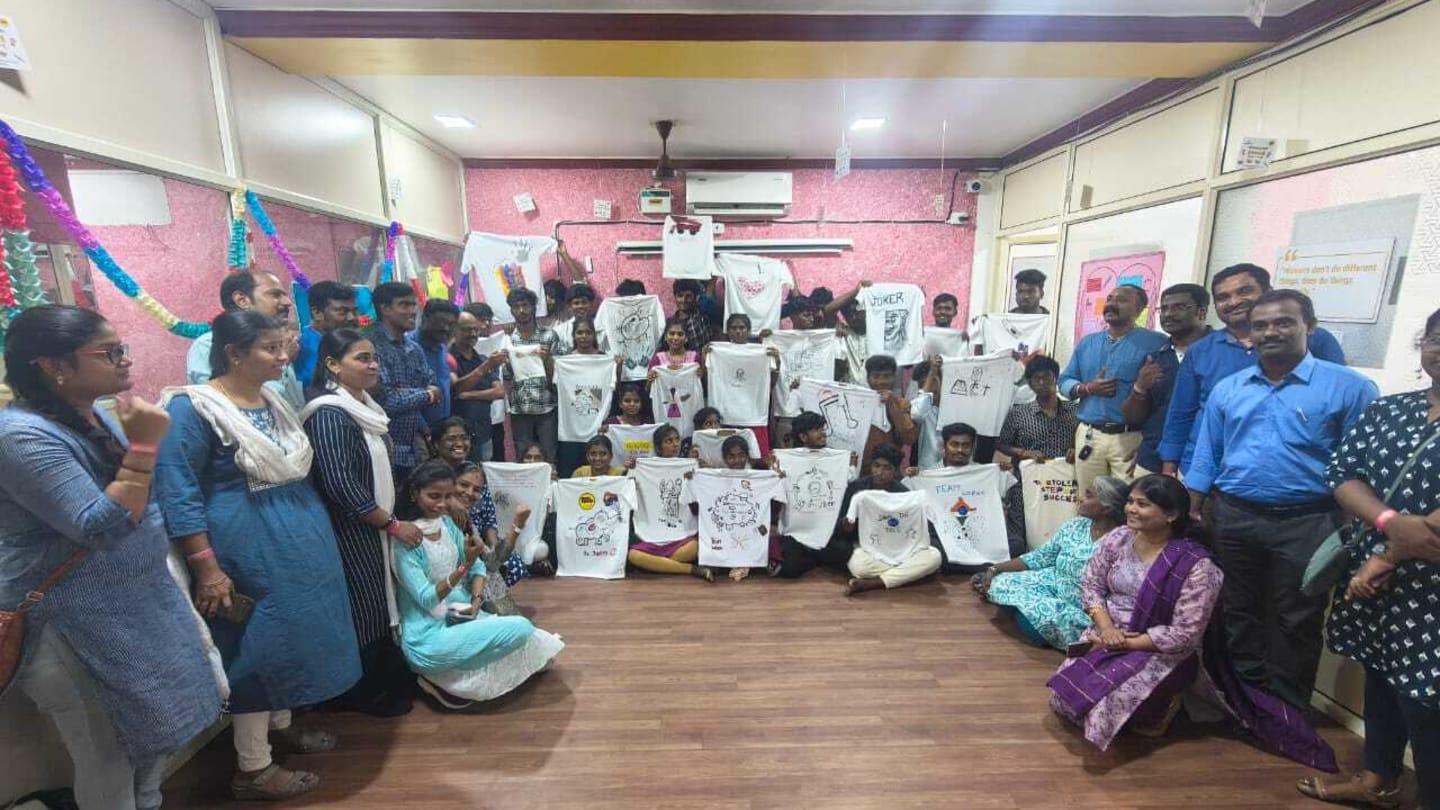 VML India Chennai employees showcasing hand painted T shirts alongside schoolgirls and boys who painted them during a community engagement activity