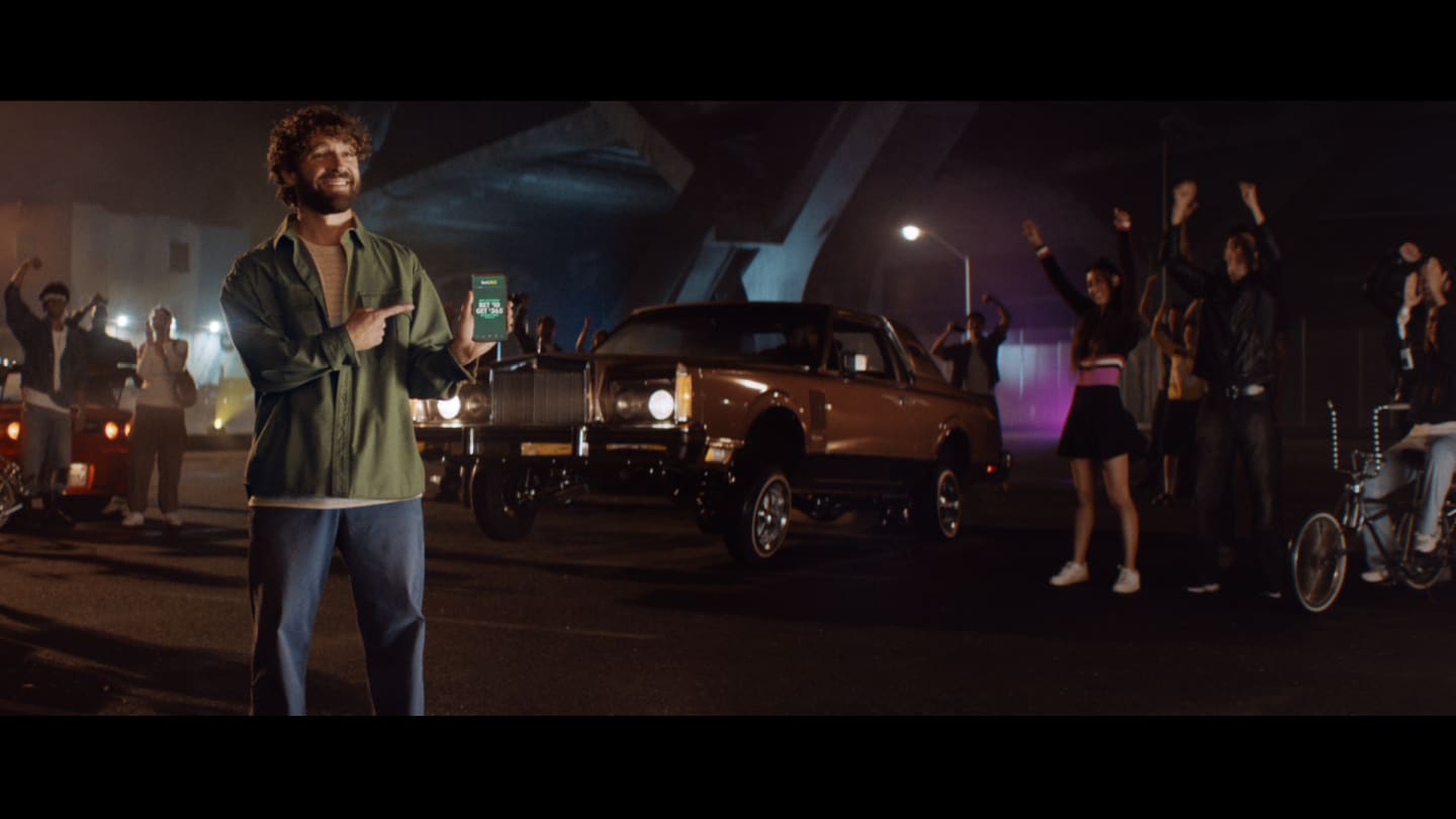 Image of a person holding a bet365 phone in front of a street race.