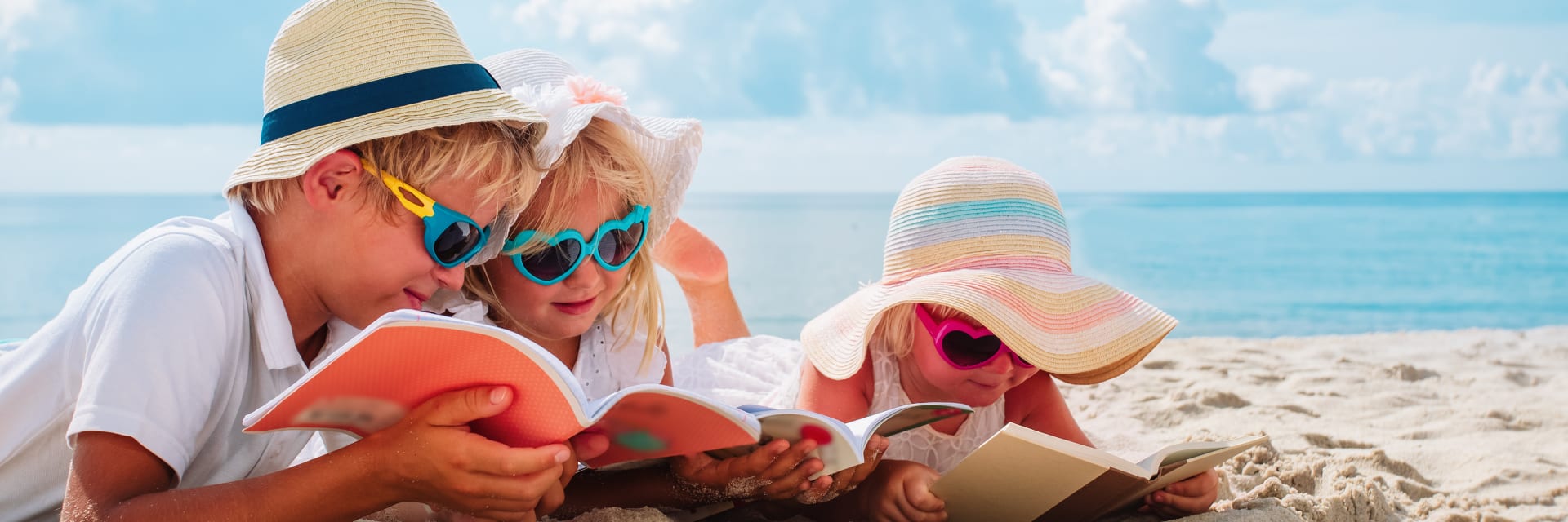 Children reading books on a beach