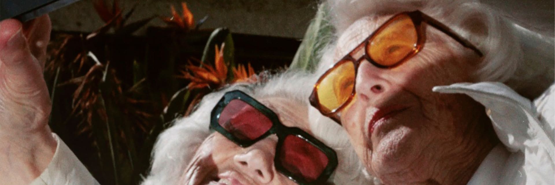 Two older women with white, short hair wearing sunglasses smile and pose for a selfie.