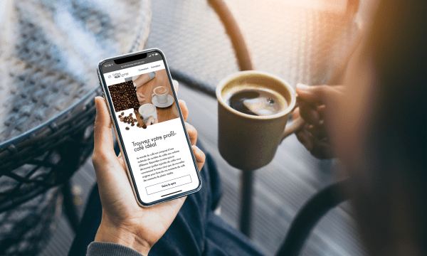 person with cup of coffee in one and mobile phine in the other hand