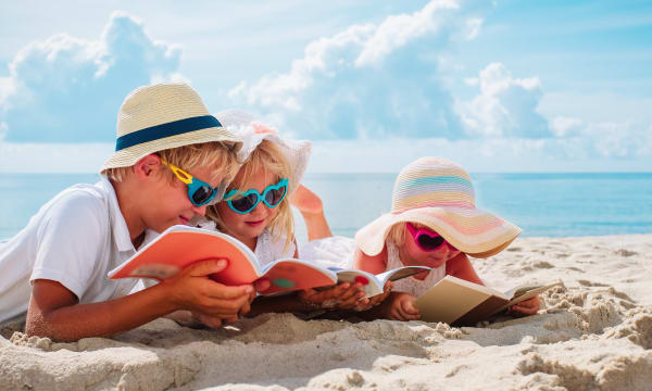 Children reading books on a beach