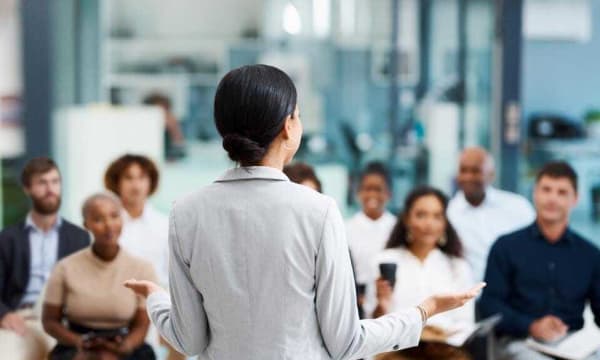 Back of woman with black hair in a bun teaching a class