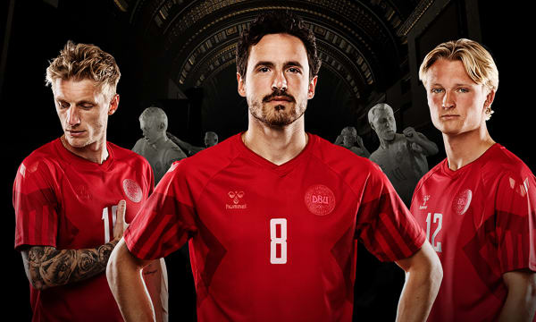 Three men wearing red soccer jerseys pose with serious expressions in front of a black backdrop.