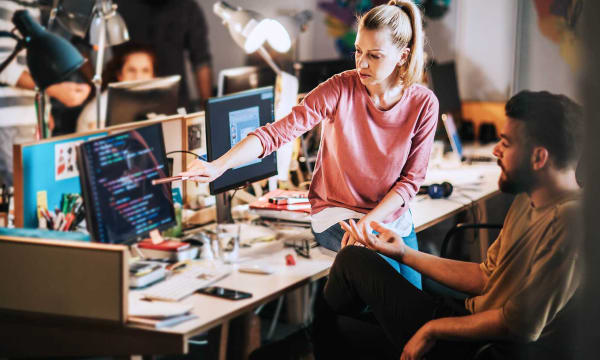 Two people looking at a screen with coding