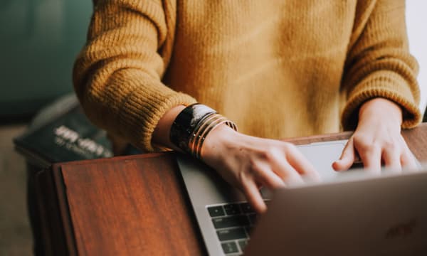 Person in yellow jumper on a laptop