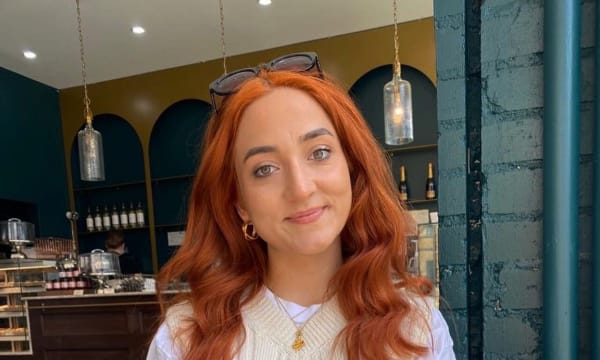 Image of Lisandra Radu, the lead on the Catalyst Academy. Lisandra is holding a very large iced coffee and the image was taken in Toronto, recently after dying her hair bright orange