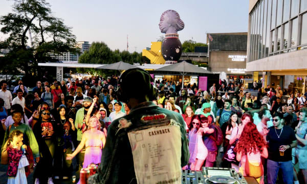 Gen Z crowd at outdoor party dancing to DJ
