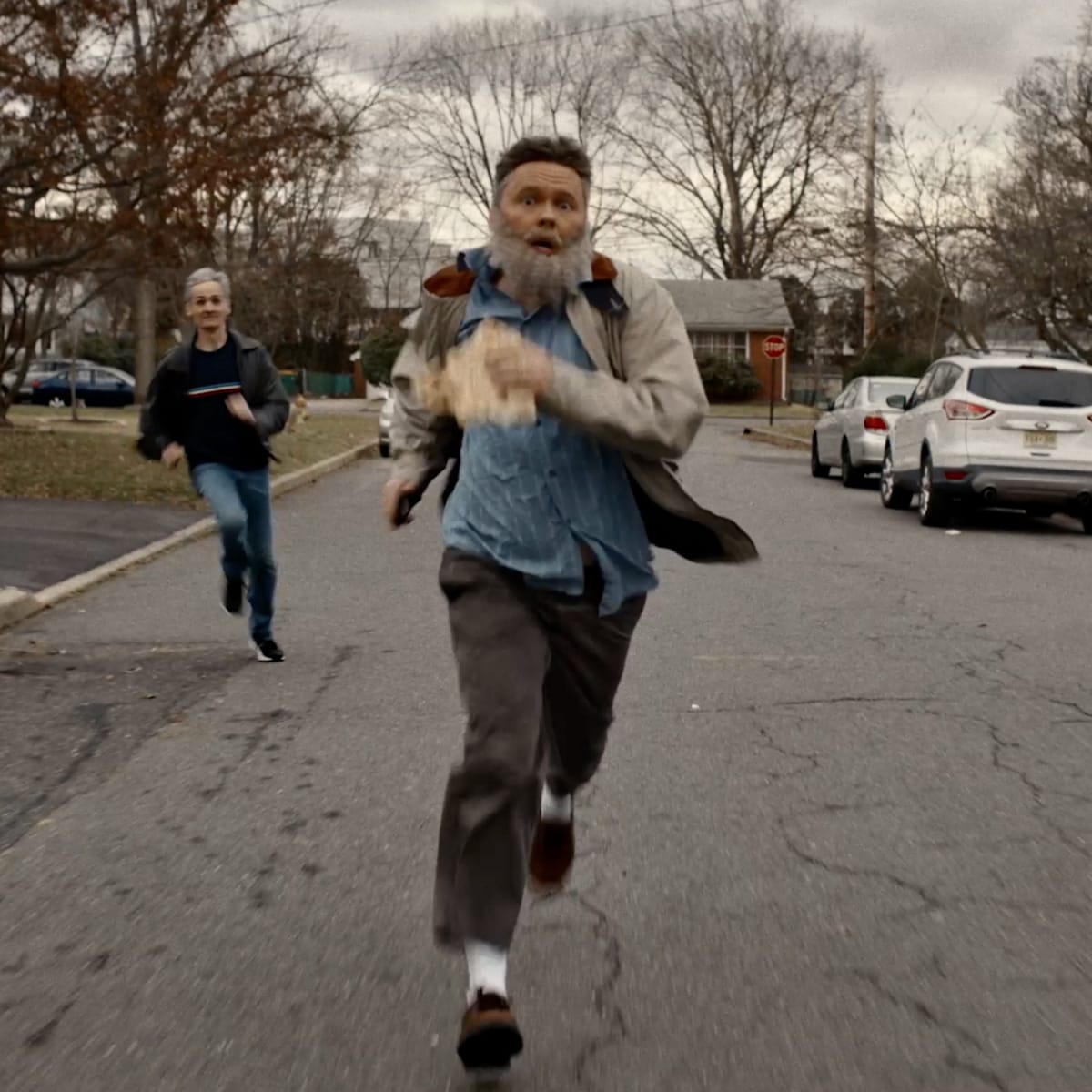 man running in the streets followed by another person running behind