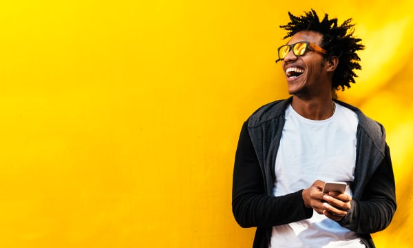 man with mobile phone in front of shiny yellow painted wall