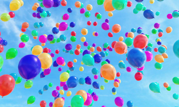 Multiple multi-coloured balloons released in the sky