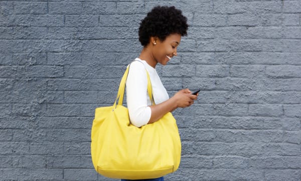 Smiling woman with iPhone and big yellow bag