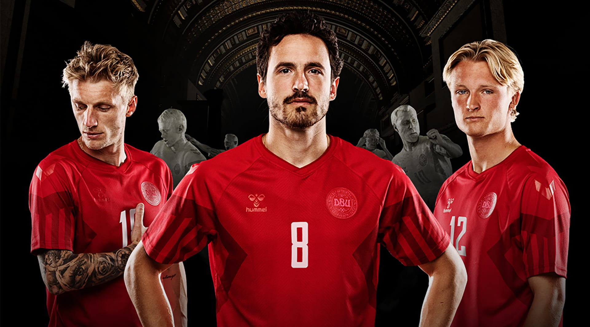 Three men wearing red soccer jerseys pose with serious expressions in front of a black backdrop.