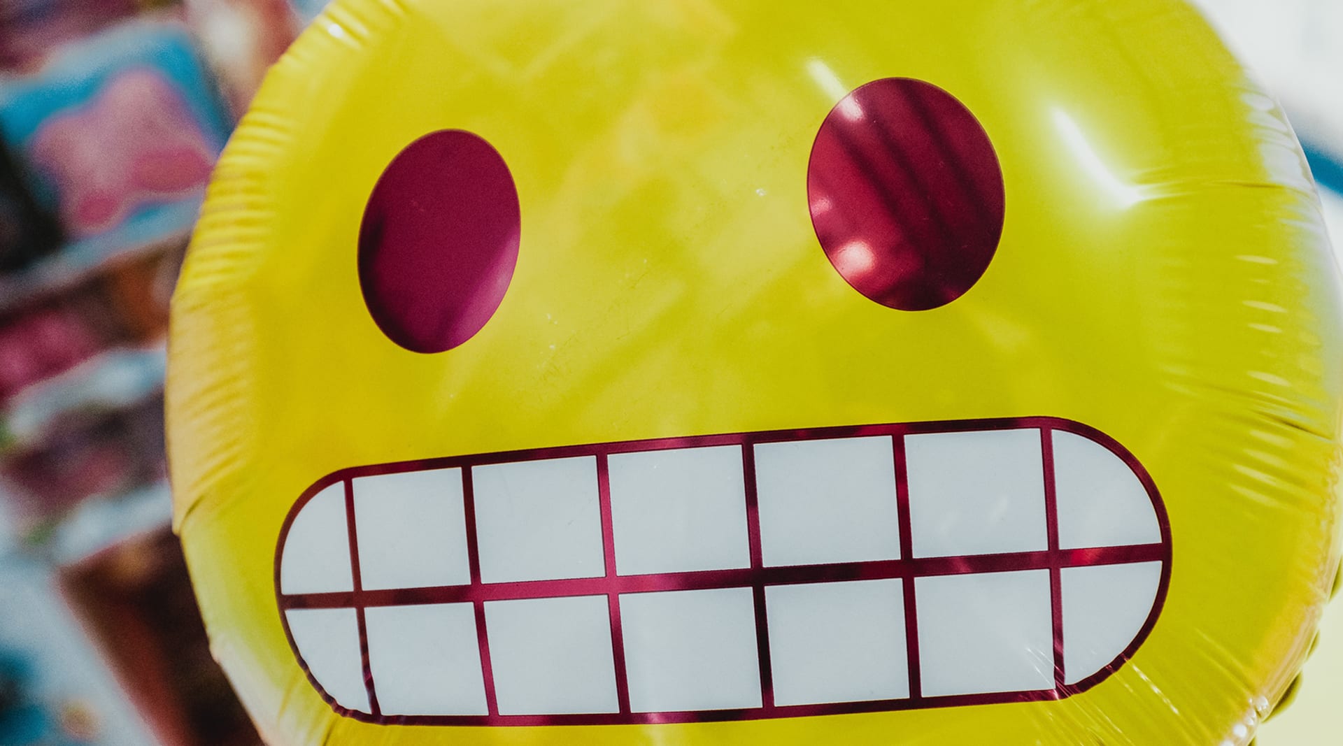 A yellow balloon, up close, with a grimace emoji expression.